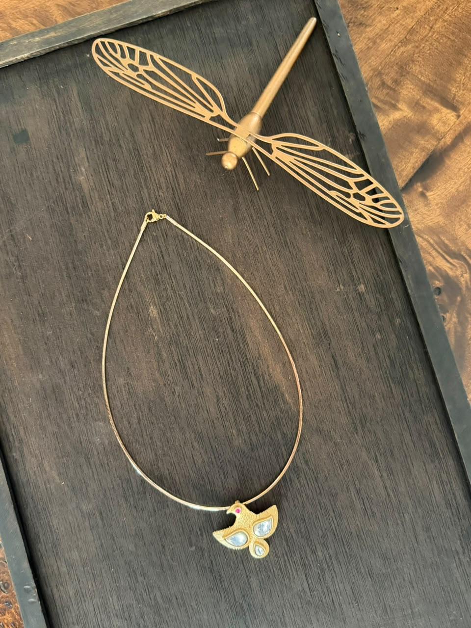 Bird Pendant with brass chain on a wooden display tray