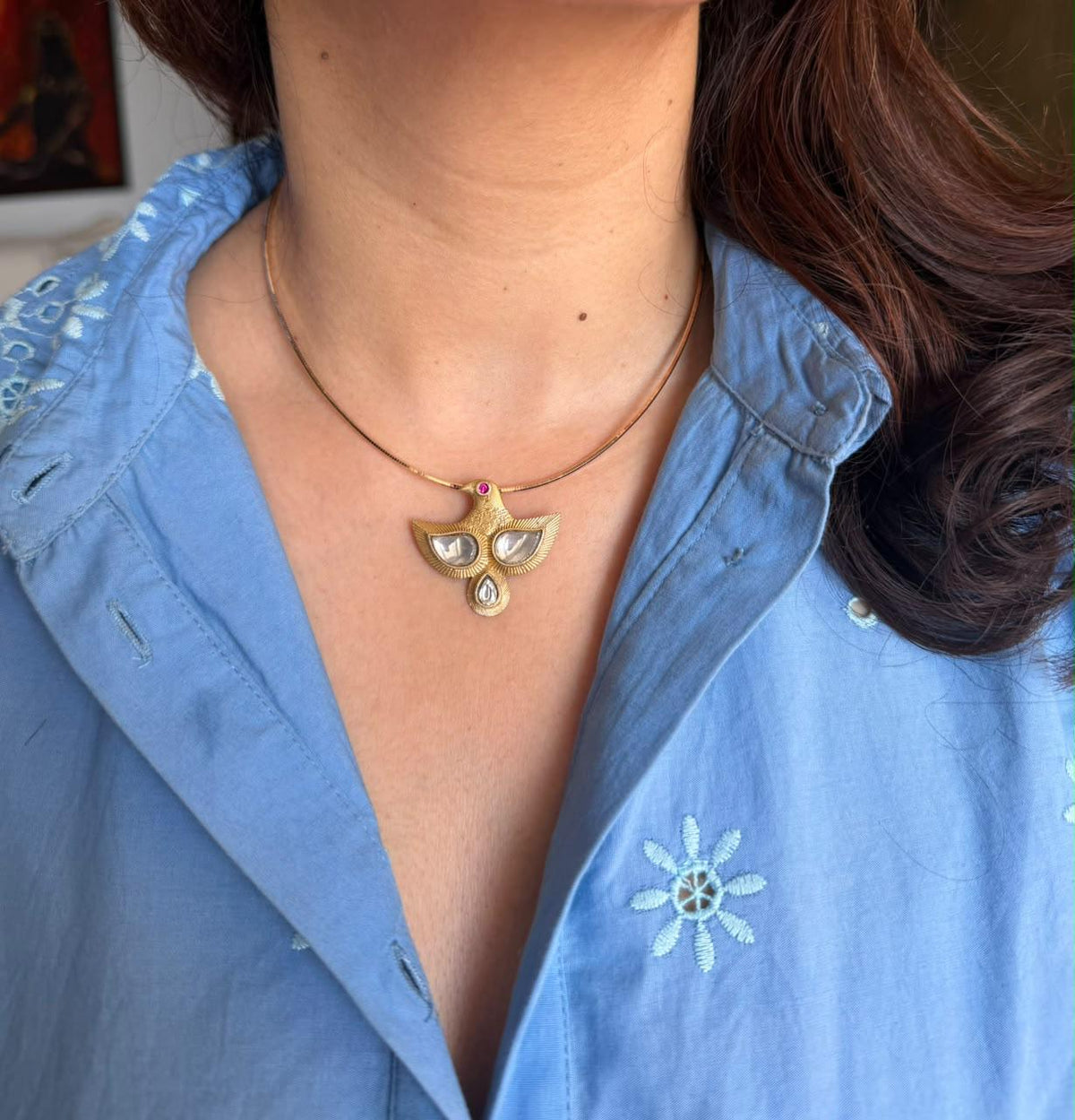 Bird Pendant and brass chain worn with a blue shirt